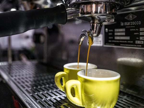 two yellow coffee cups being filled on an espresso machine