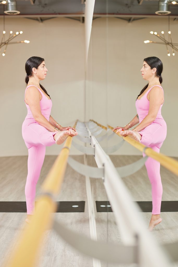 Woman in pink leotard standing at barre