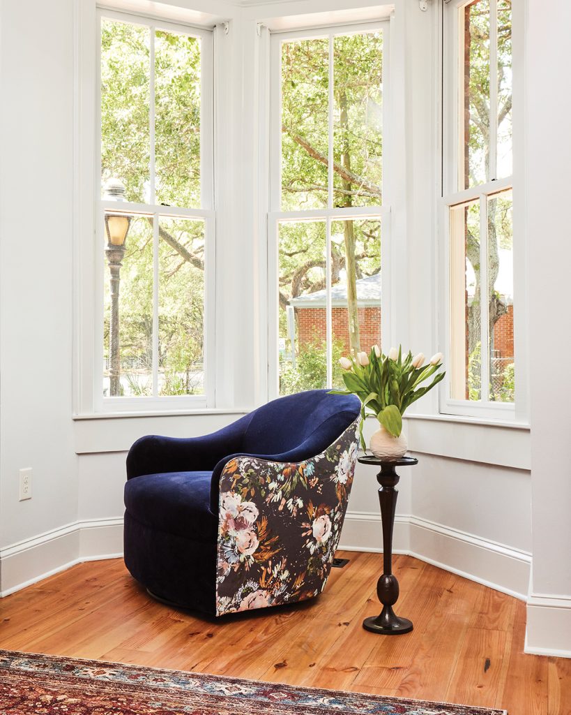 Dark blue lounge chair in reading nook and tall windows