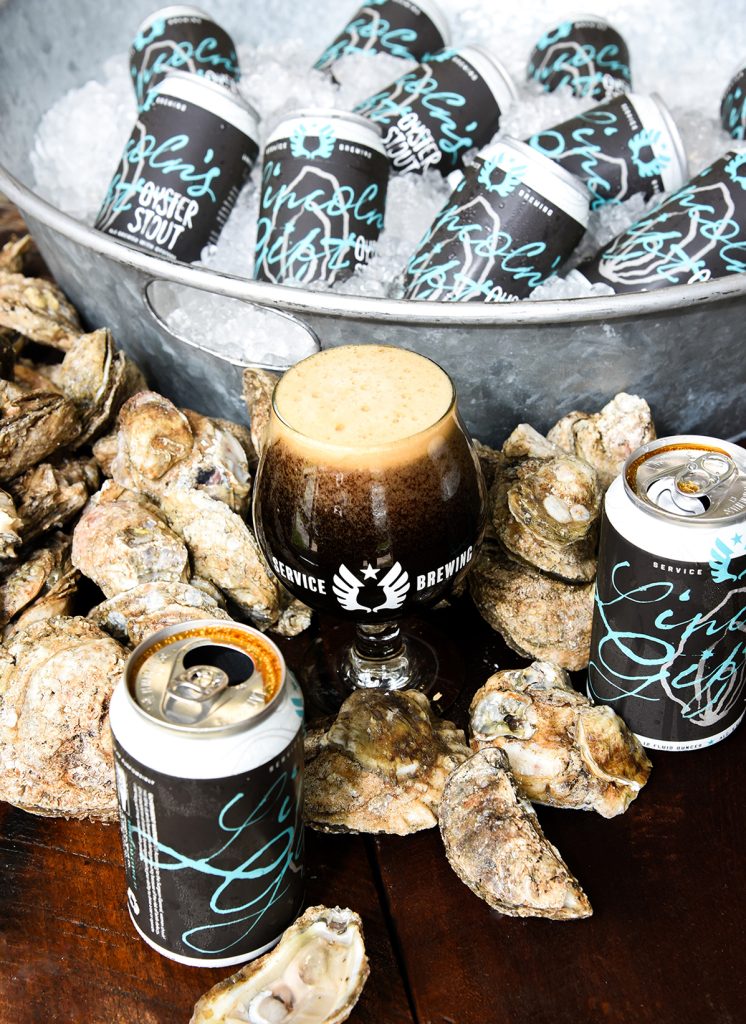 cans of beer on ice surrounded by oysters and pint glasses of stout