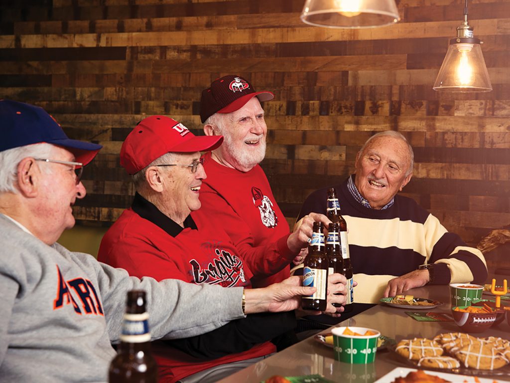 old men saying cheers with beer at a bar