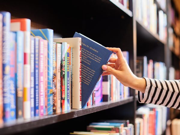 A woman's hand pulling a book off a shelf lined with books