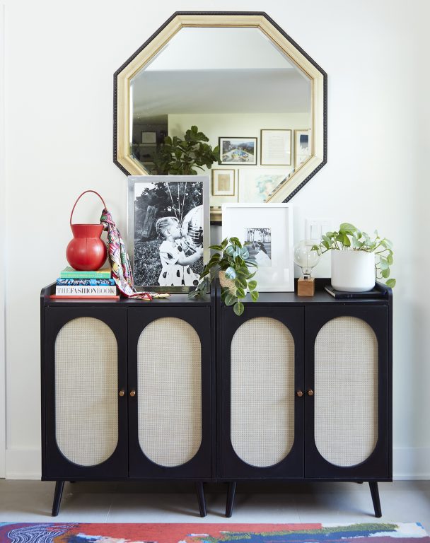 On octagonal mirror hanging above a contemporary dark wood entryway cabinet