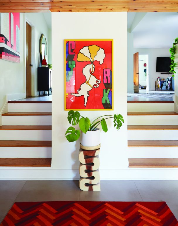 Colorful, whimsical painting of a horse hanging on a narrow wall flanked by two sets of stairs
