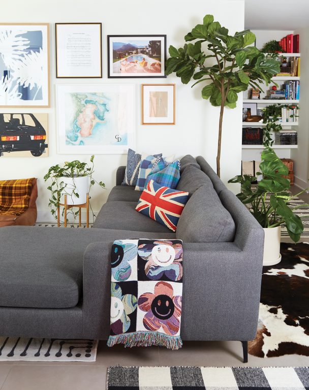 Gray couch with British flag pillow and smiley face throw in a living room with a cow hide rug