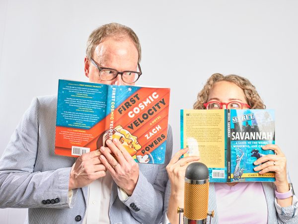 man and woman peeking out from behind books they are holding up