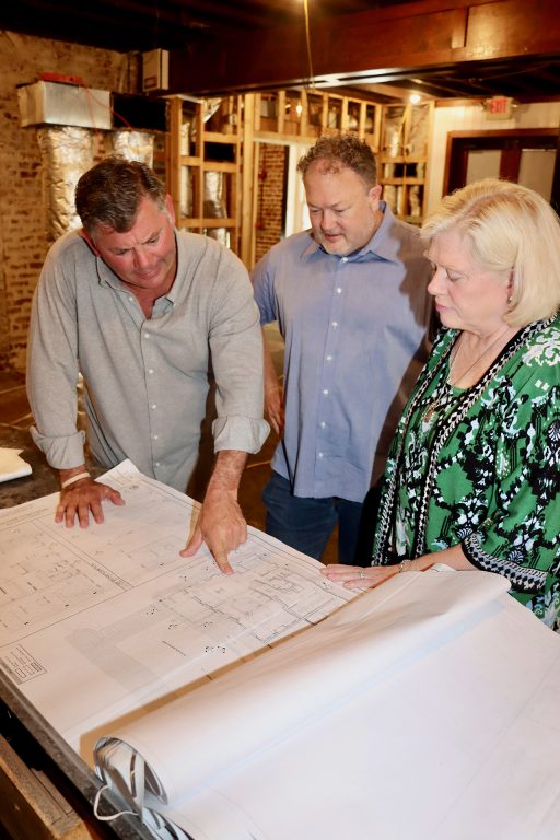 two men and a woman looking at building plans