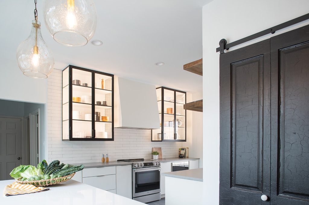 A kitchen with open. lighted cabinets and subway tile