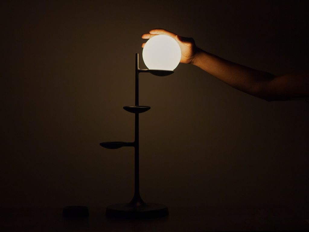 Hand reaching for the bulb of a floor lamp