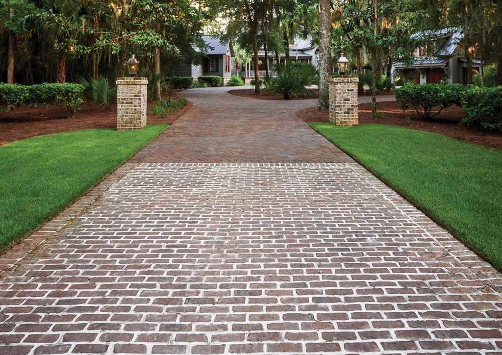 A brick driveway with grass and trees