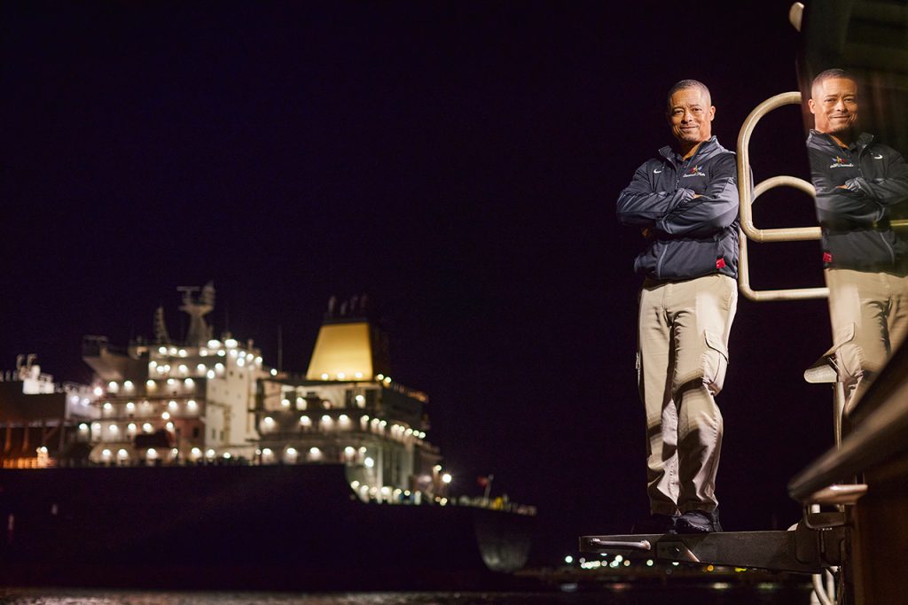 Man standing on a dock with a container ship in the background