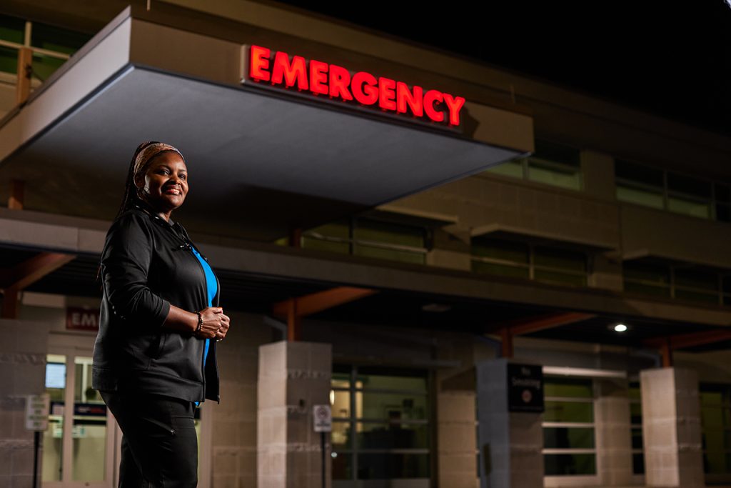 Nurse standing outside in front of a hospital emergency room sign
