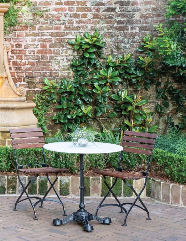 A magnolia espalier growing next to a fountain in a courtyard at Zero George Hotel