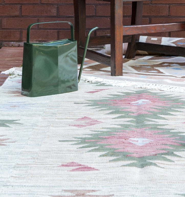 Green watering can on an outdoor rug