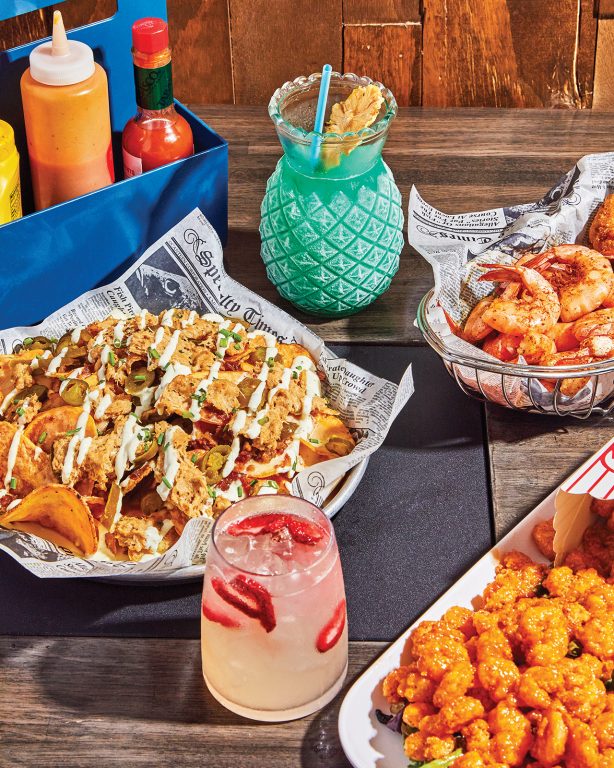 A plate of nachos, popcorn shrimp and cocktails on a table