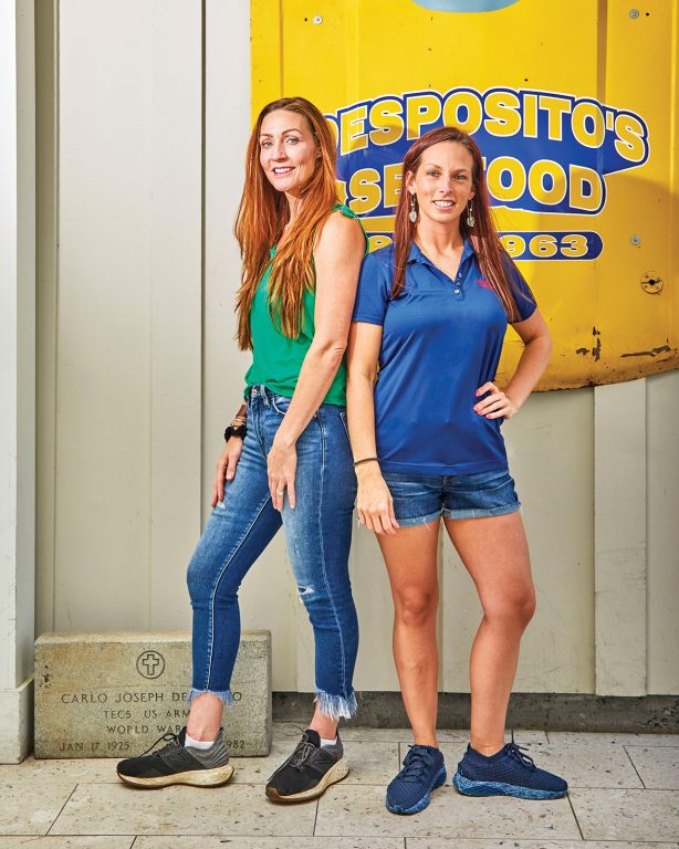 Two women standing back to back and smiling