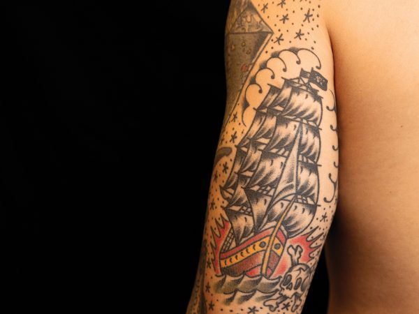 A pirate ship tattoo on the back of a man's upper arm