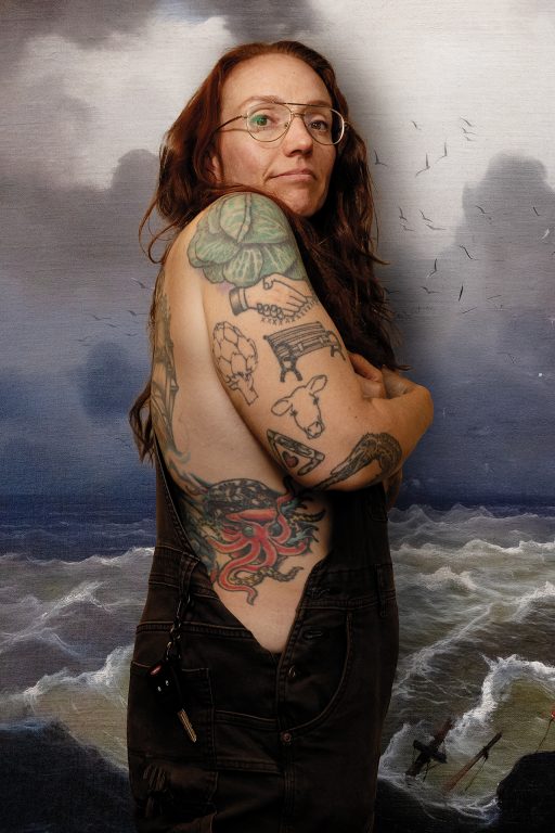 A woman wearing glasses and showing off the tattoos on her arm and side