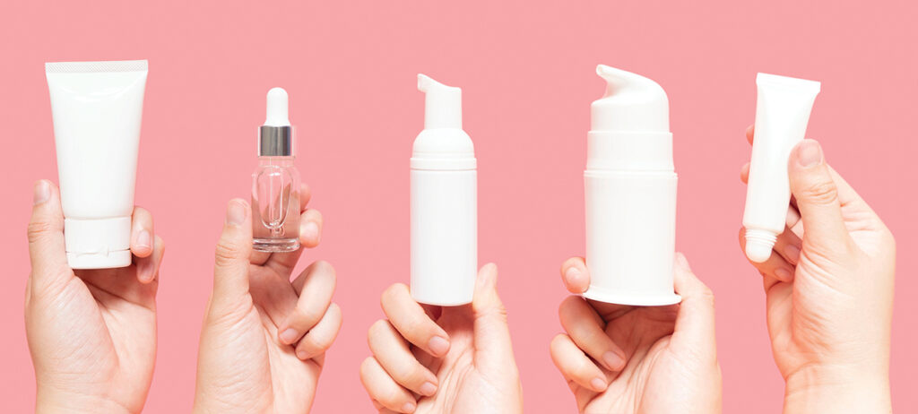 honds holding up bottles of skincare lotions and serums