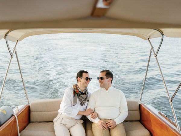 Two men sitting on a boat and looking at each other and smiling