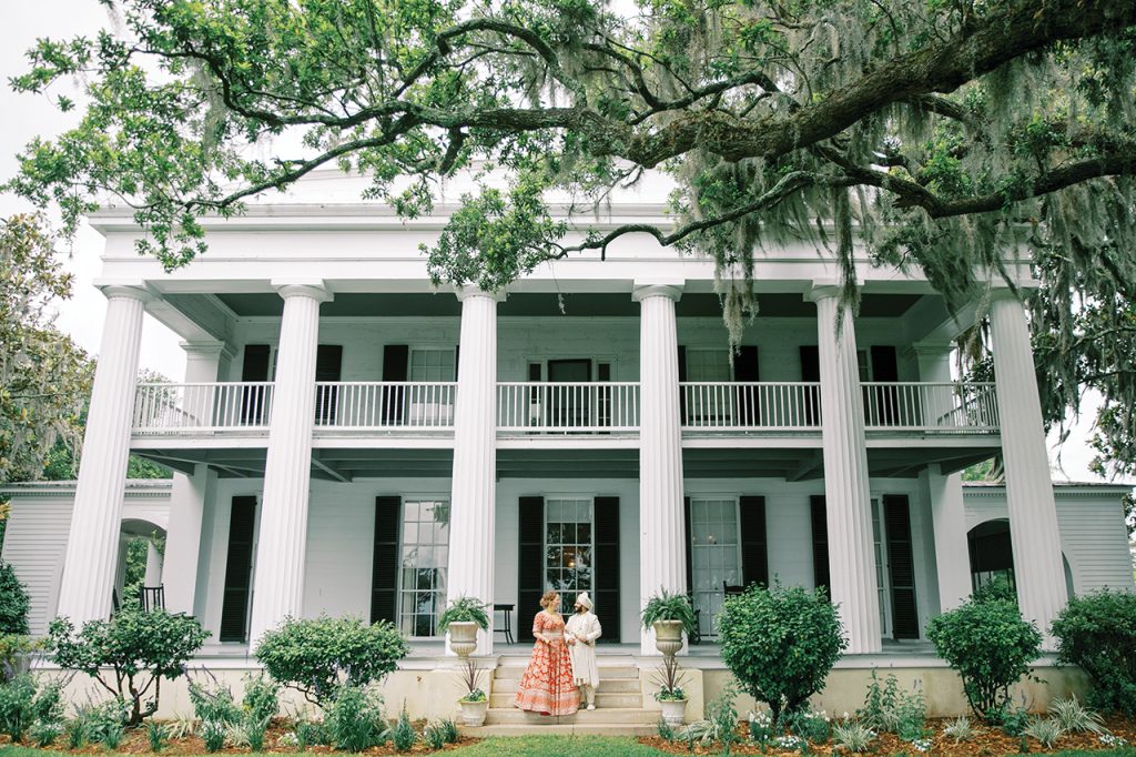 A bride and groom standing on the steps of the mansion at Beaulieu