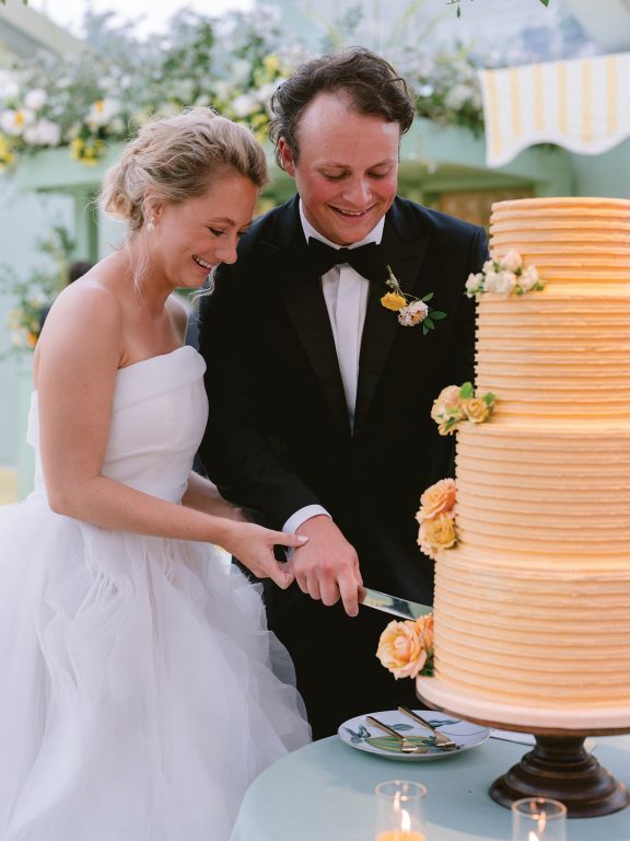 A bride and groom cutting their four-tier golden-yellow wedding cake