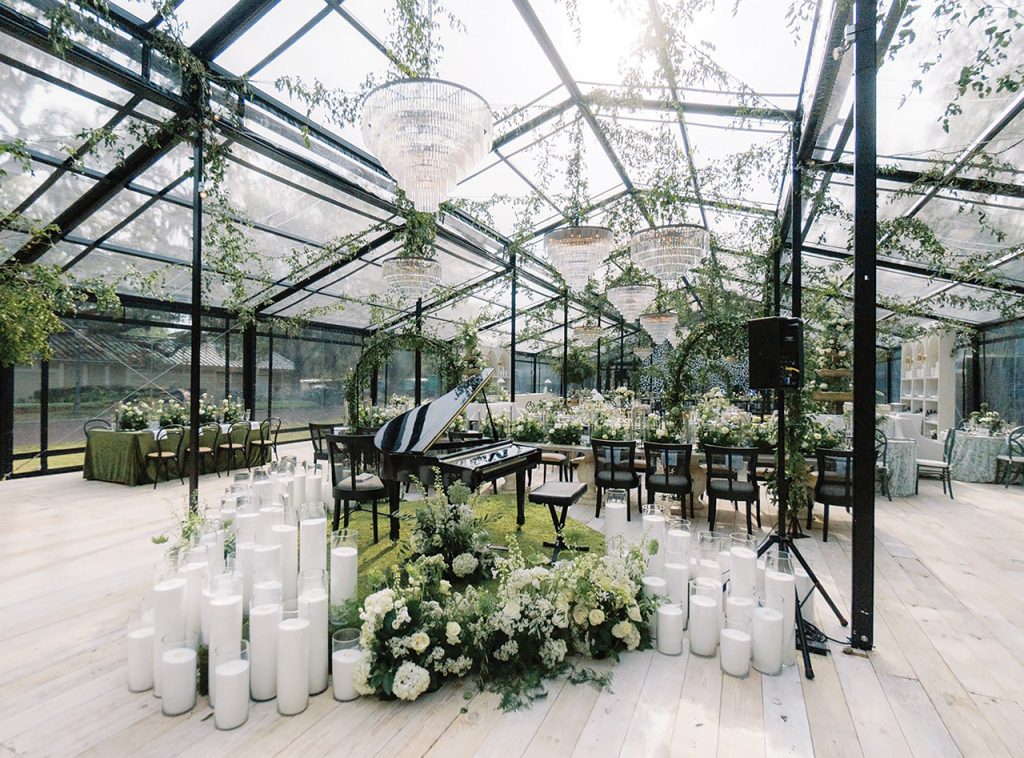 Garden/atrium structure with double-pitched roof line, clear vinyl and black framework set up for a wedding