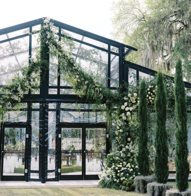 Garden/atrium structure with double-pitched roof line, clear vinyl and black framework set up for a wedding