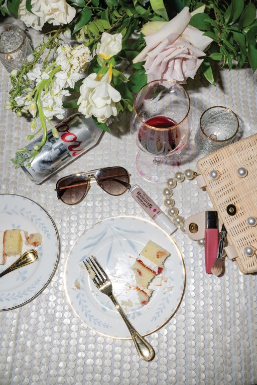 Drinks, plates with half-eaten cake, makup and flowers on a table