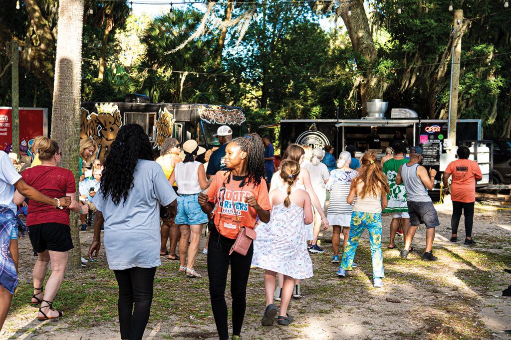 People line dancing and getting food from food trucks at a festival