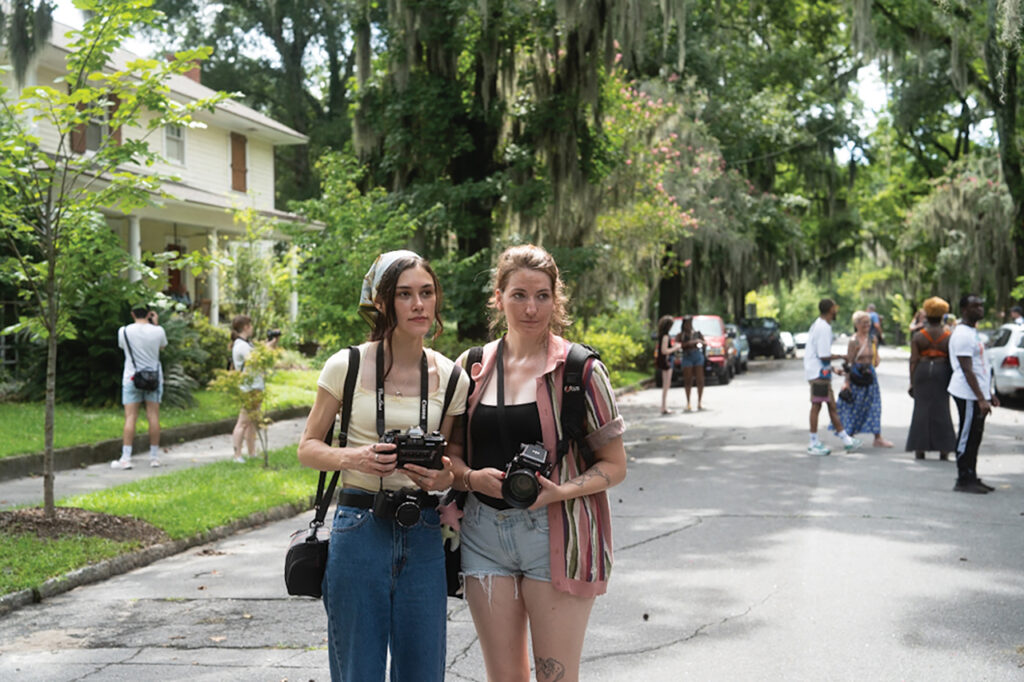 Two women holding cameras and standing in the street