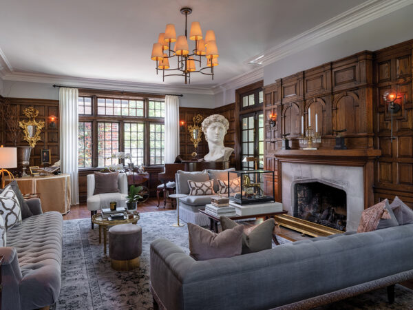 a living room in a historic home with a large fire place, a giant bust sculpture and detailed wood paneling