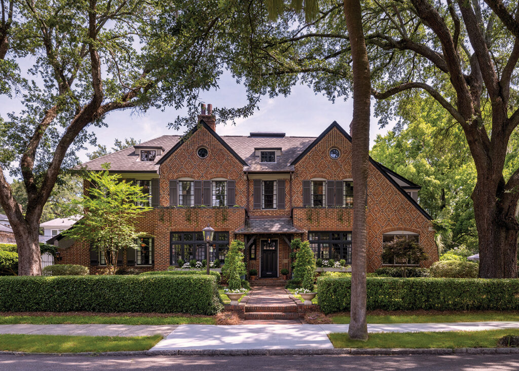 reddish-brown brick Tudor style house with brown shutters