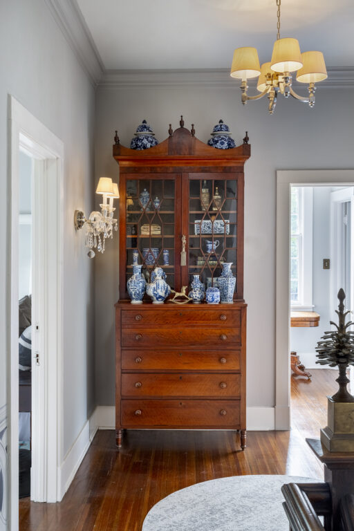 a dark wooden curio cabinet with numerous blue-painted vases