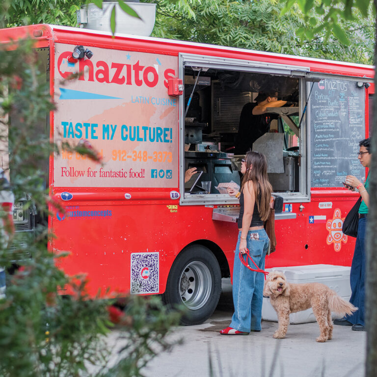 A woman with her dog, ordering at a food truck
