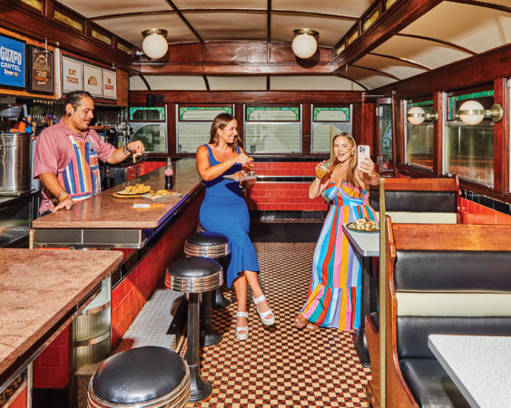Two women and a man eating in a 1950s themed diner