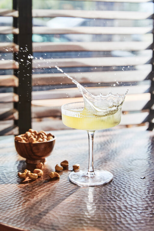 A martini next to a bowl of cashews