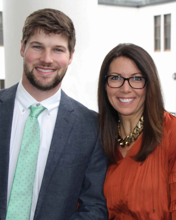 A woman and her adult son standing together smiling