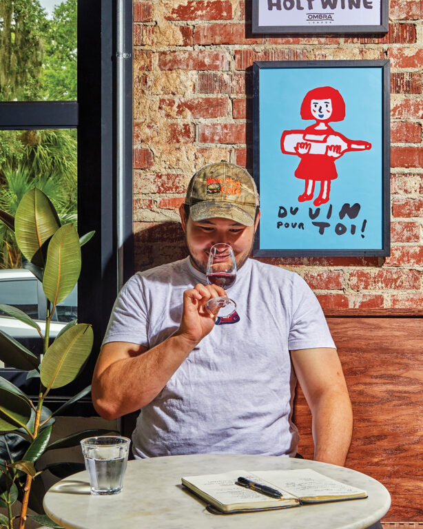A man sitting at a table sipping wine