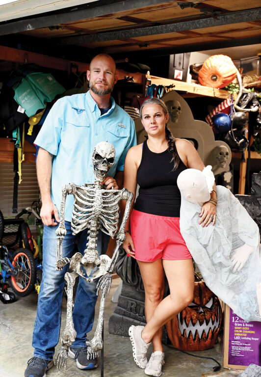 A man and woman standing in a garage full of halloween decorations