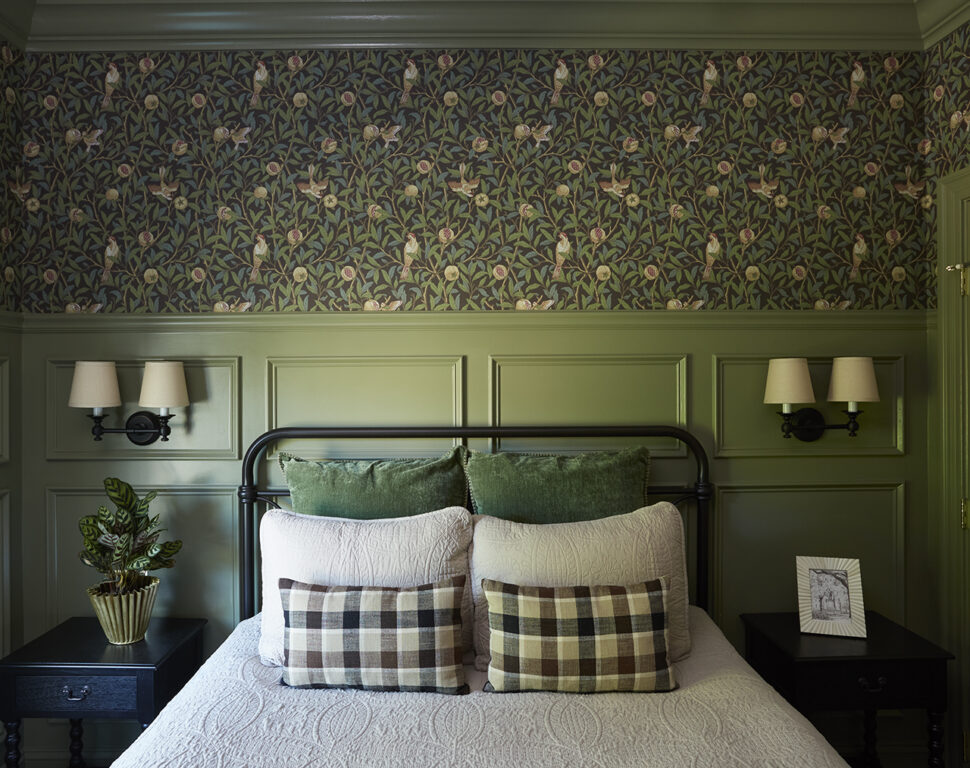 Bedroom with metal frame full bed, green wainscoting and Morris & Co. wallpaper