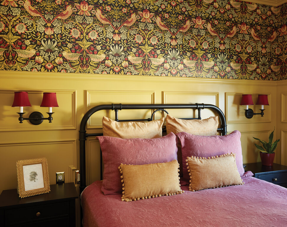Bedroom with metal frame full bed, goldenrod wainscoting and Morris & Co. wallpaper