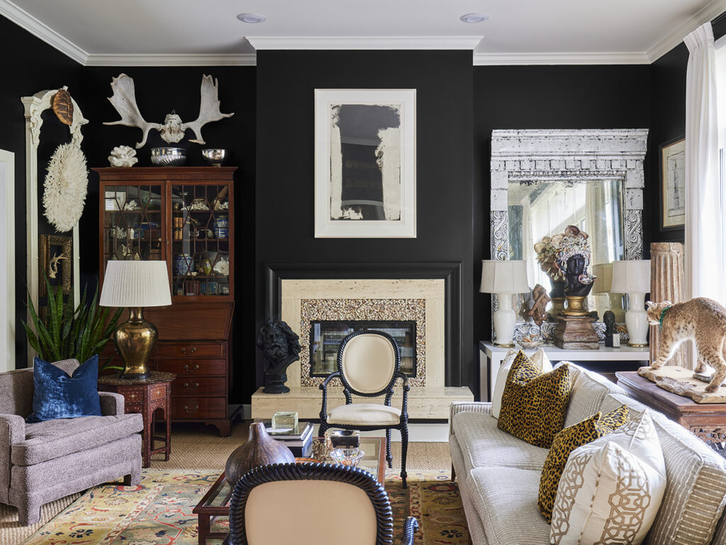A living room with black walls, leopard print pillows and a taxidermied bobcat