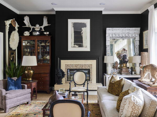 A living room with black walls, leopard print pillows and a taxidermied bobcat