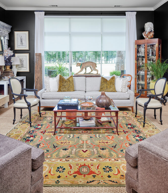 A living room with black walls, leopard print pillows, a taxidermied bobcat and colorful rug