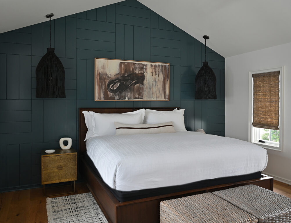 Bedroom with dark greenish blue accent wall and black whicker hanging lights