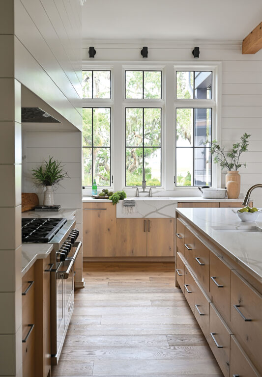 Kitchen with marble countertop, natural wood cabinets, light wood floors and white shiplap walls