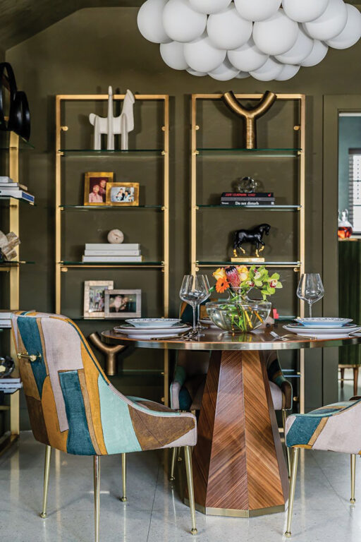Dining room with round dining table, colorful chairs and chandelier made of numerous white spheres