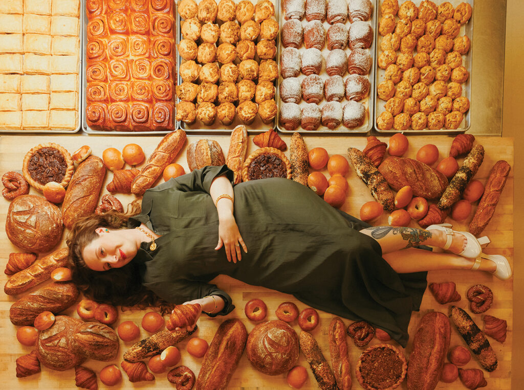 Auspicious Baking Co. owner Katie Bryant lays on a table loaded with baked goods