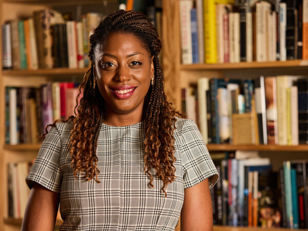 Chassidy Malloy smiling and standing in front of a bookshelf